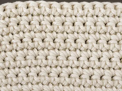 Close-up of a cream single crochet swatch showing dense, even columns of V-shaped stitches.